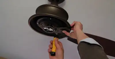 Electrician installing ceiling fan mounting bracket and fixture in Milwaukee, WI