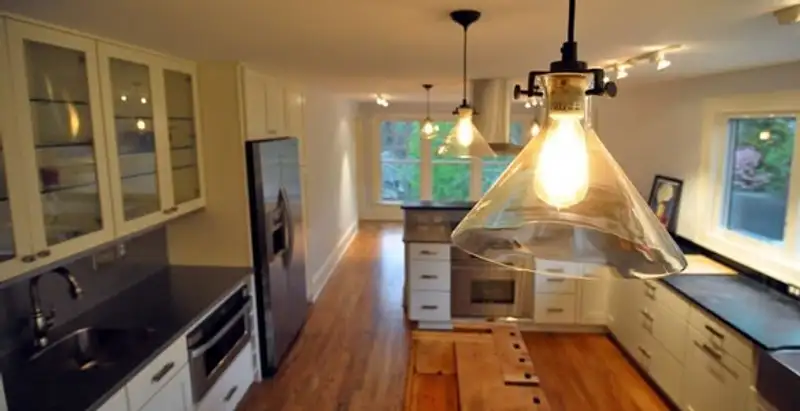 Residential electrician installing modern indoor light fixture in a home in Milwaukee, WI